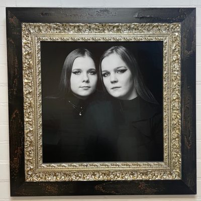 Zwart-wit portret van twee zussen in een zilverkleurige barokke lijst met donkere buitenlijst