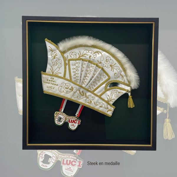 Witte carnavalssteek met goudborduursel en een medaille in een verdiepte lijst met donkergroene achtergrond
