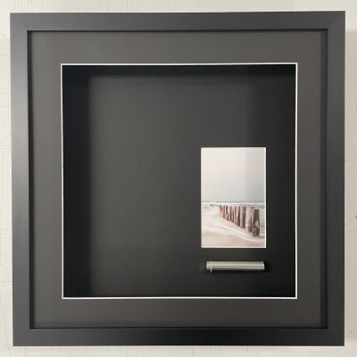 Gedenkkistje voor een huisdier met een strandfoto en een klein aandenken in een verdiepte zwarte lijst