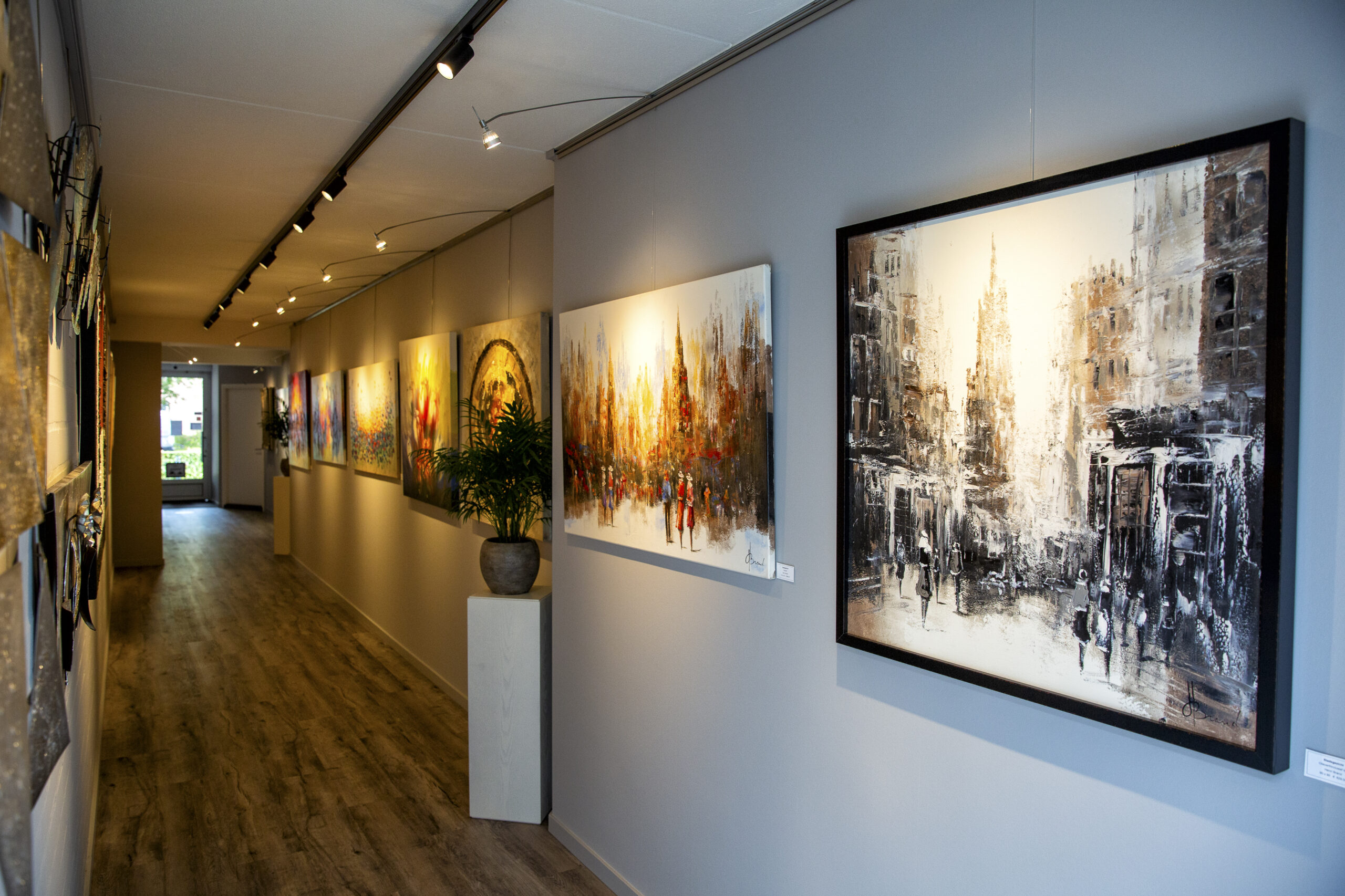 De galerie van Heijnen Decor in Nederweert-Eind met ingelijste stadsgezichten aan de wand onder museumverlichting