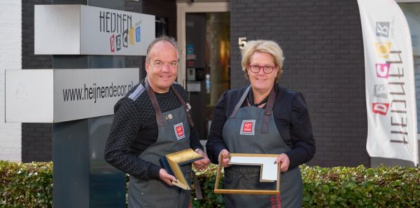 Natascha en Edward Heijnen voor de lijstenmakerij in Nederweert-Eind, ieder met een lijst in de hand